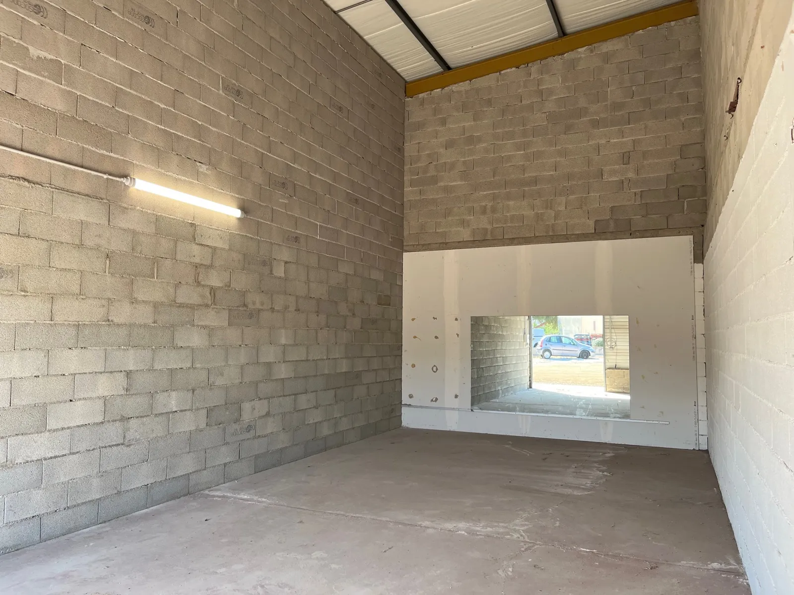 L’intérieur du local A2 : grand volume sous 6 m de hauteur, murs en parpaings et sol en béton