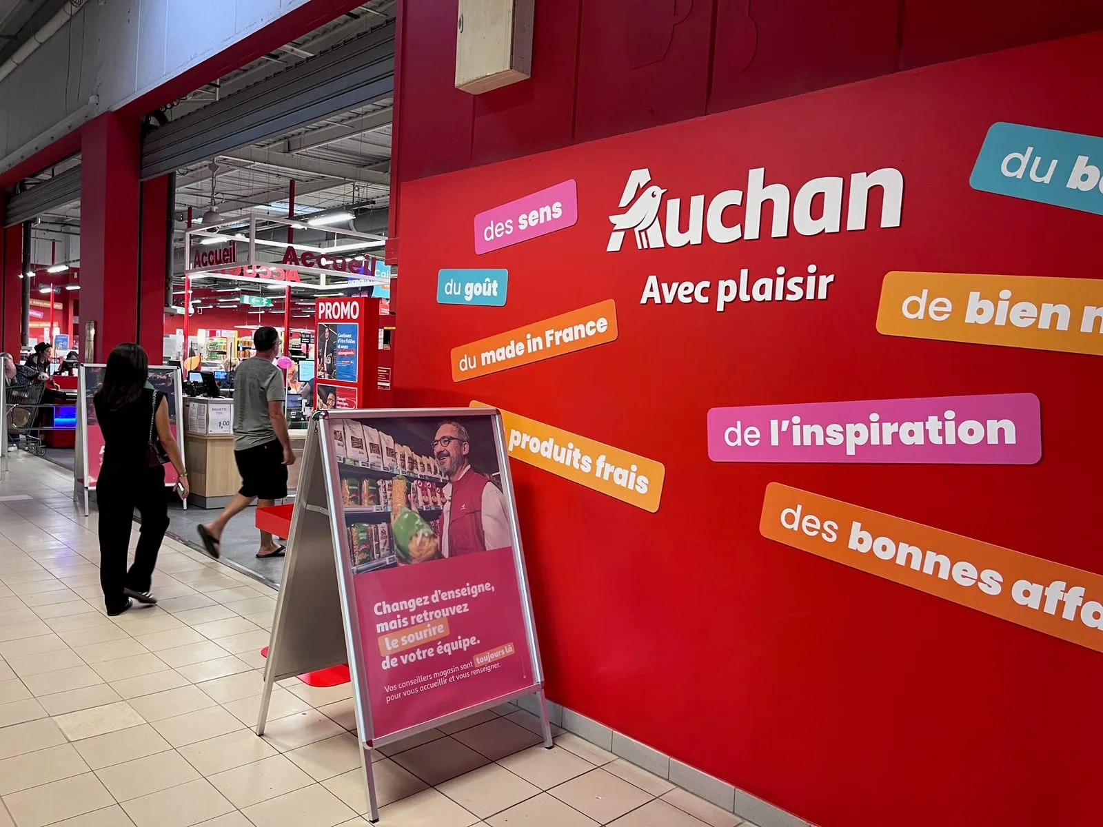 L'entrée du supermarché Auchan dans la galerie du centre commercial, son mur rouge et ses caisses