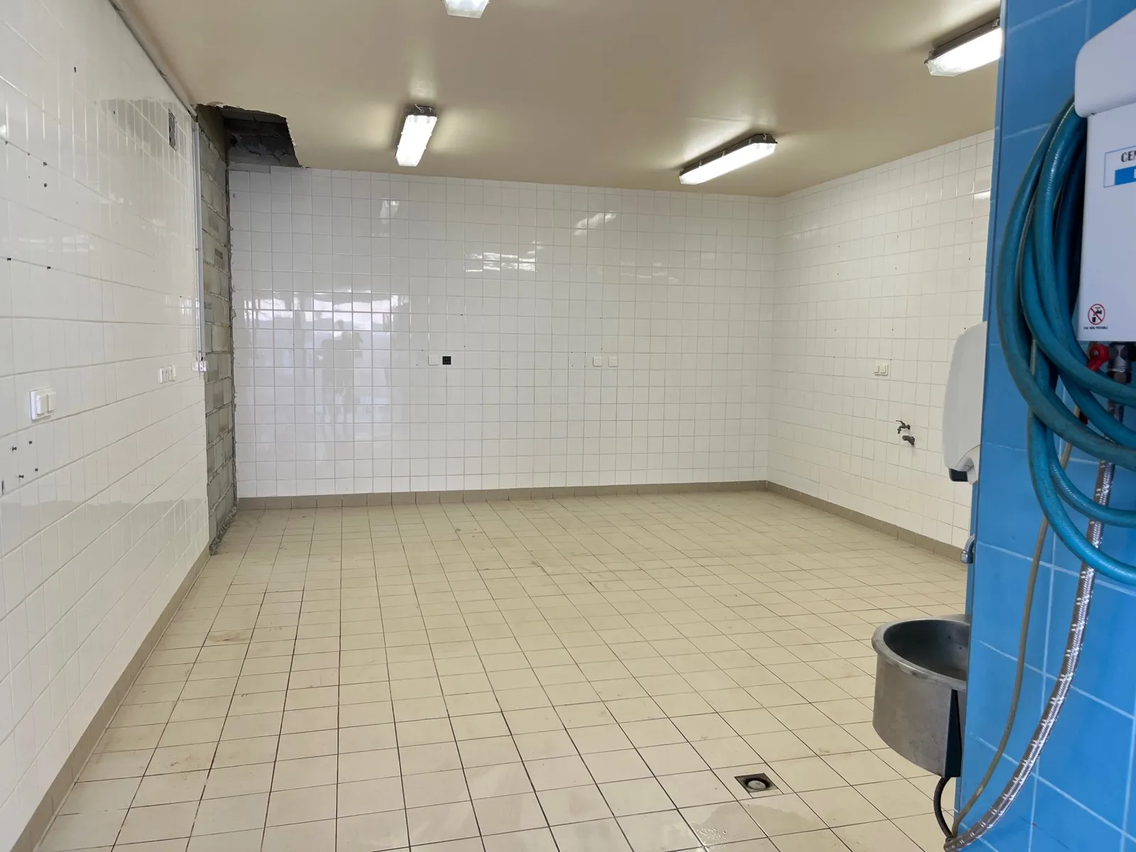 L’intérieur du local C1, entièrement carrelé du sol au plafond, avec ses réglettes d’éclairage