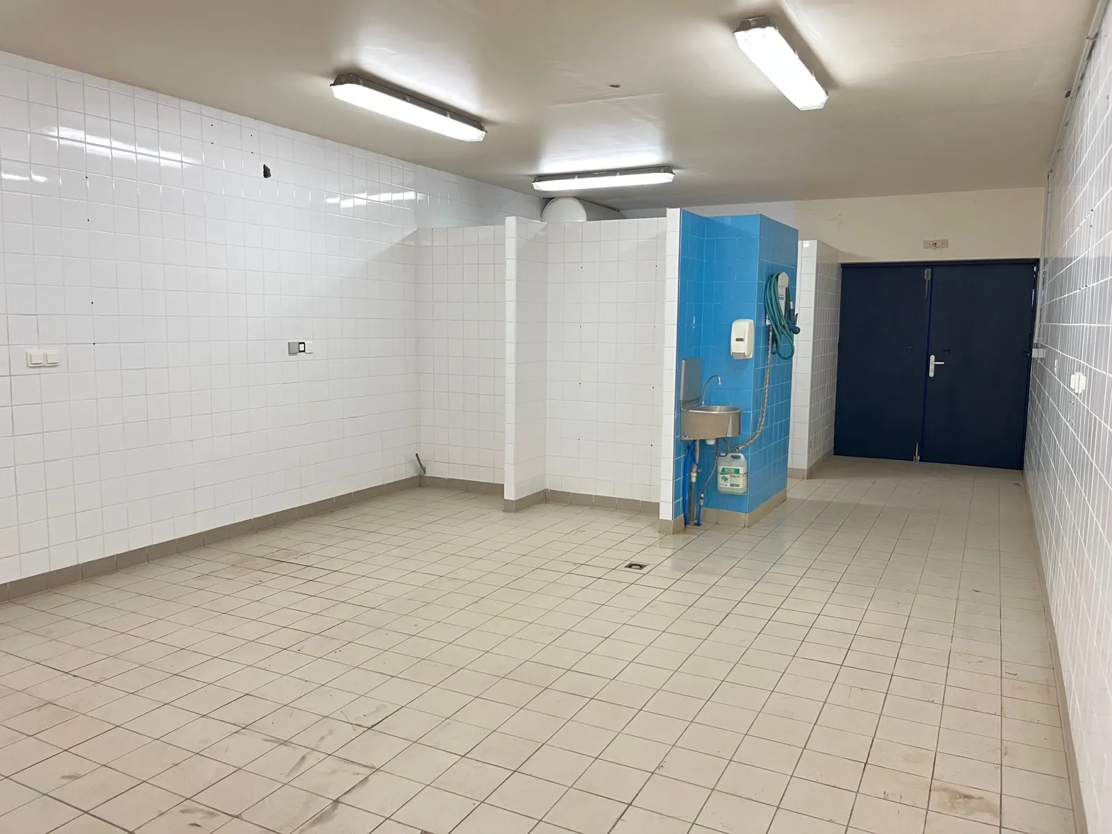 Le local C1 vu depuis le fond, avec la cloison des sanitaires et la porte à deux battants