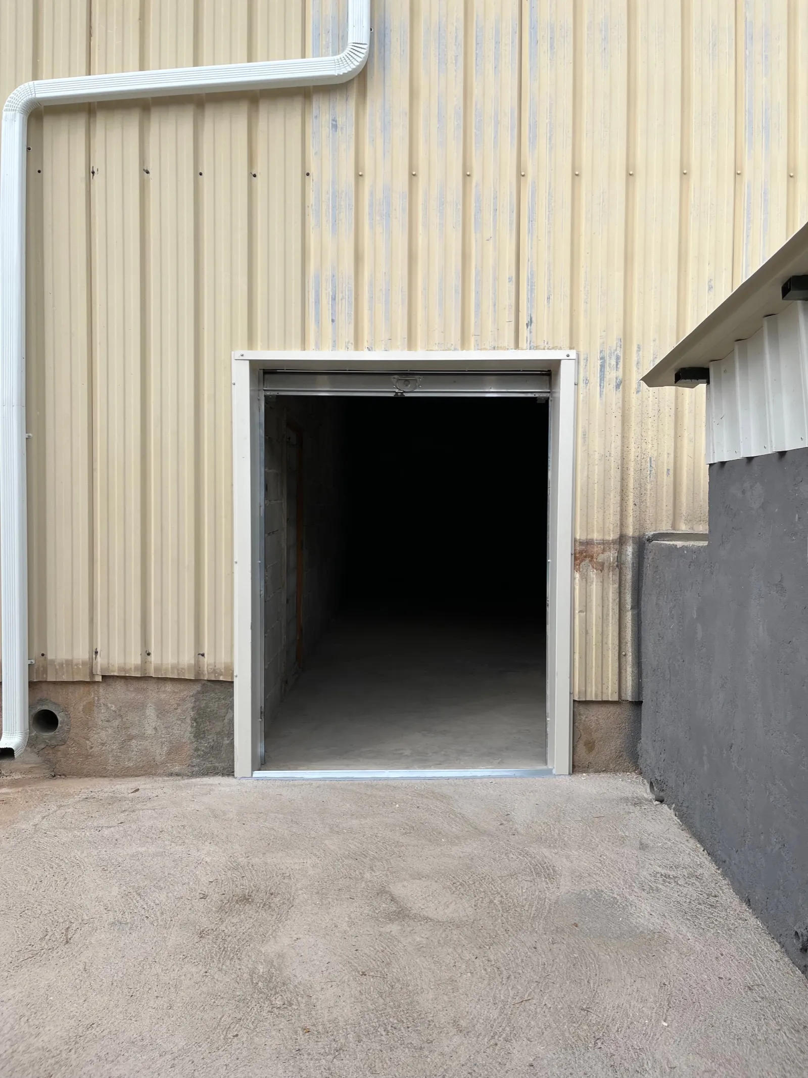 L’entrée du local C2, rideau métallique ouvert sur la façade de l’entrepôt