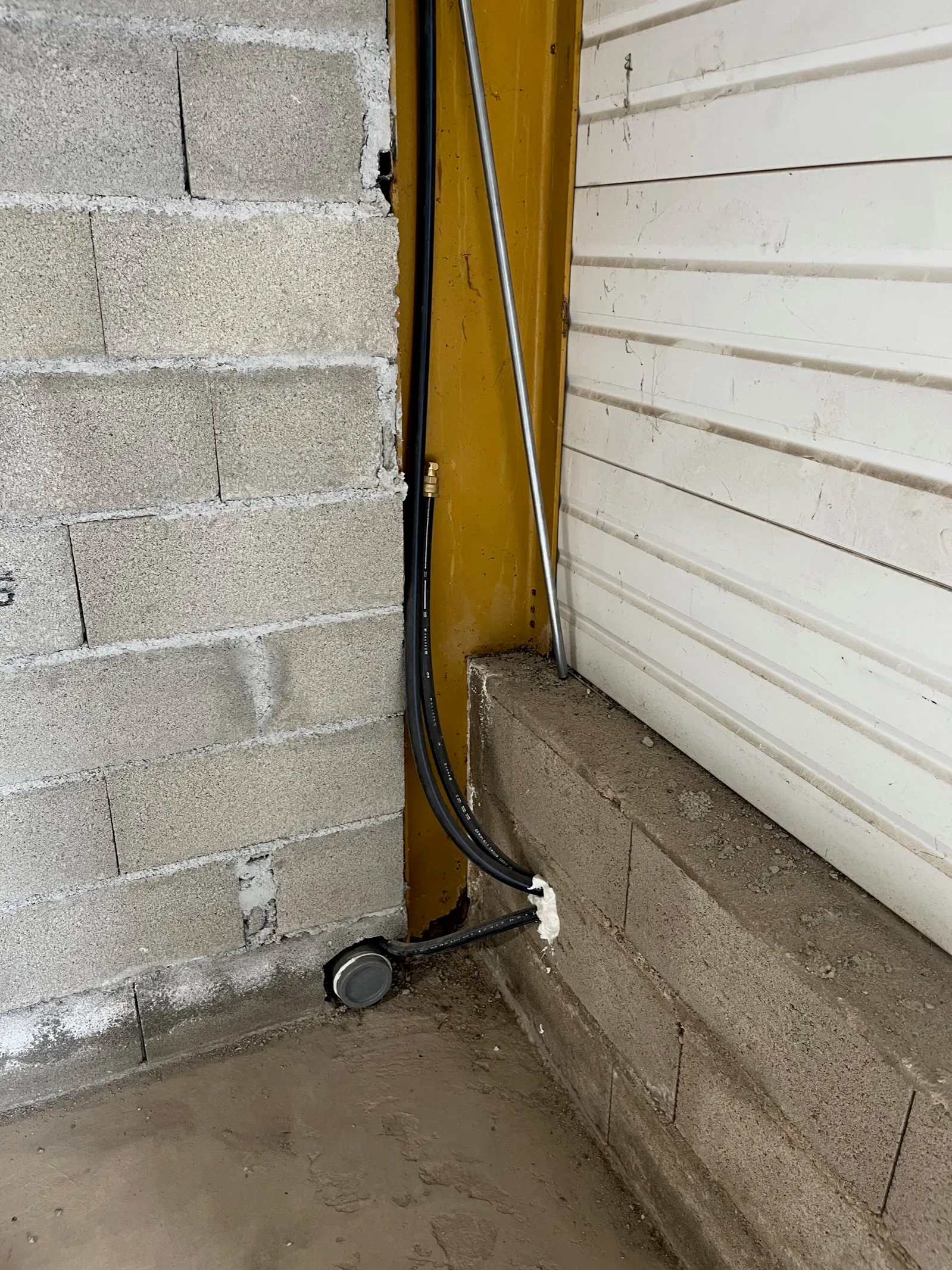L’arrivée d’eau et l’évacuation d’eaux usées du local C2, dans un angle près de la porte