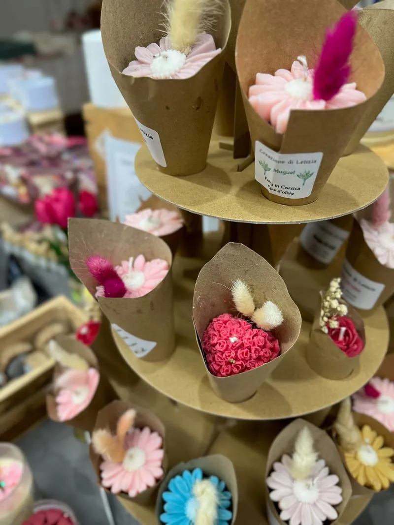 Bougies fleuries en cire d’olive présentées dans des cornets de papier kraft, sur le stand Creazione di Letizia
