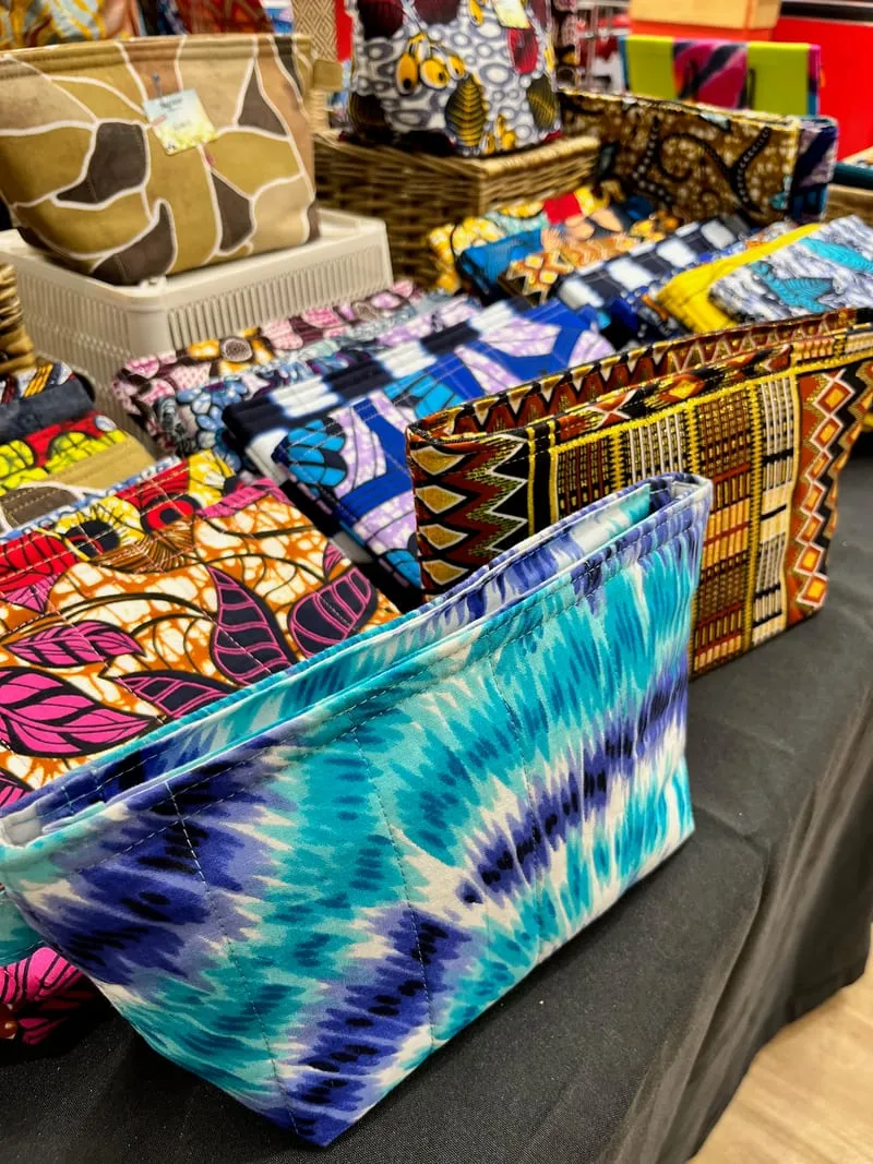 Trousses et pochettes en tissus wax aux motifs colorés, sur le stand Ovnink Inkternational