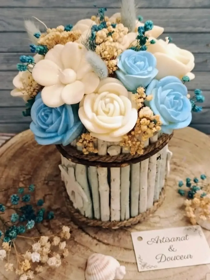 Un bouquet de bougies en forme de roses bleues et crème, dans un pot en bois flotté, sur le stand Rêves Parfaits