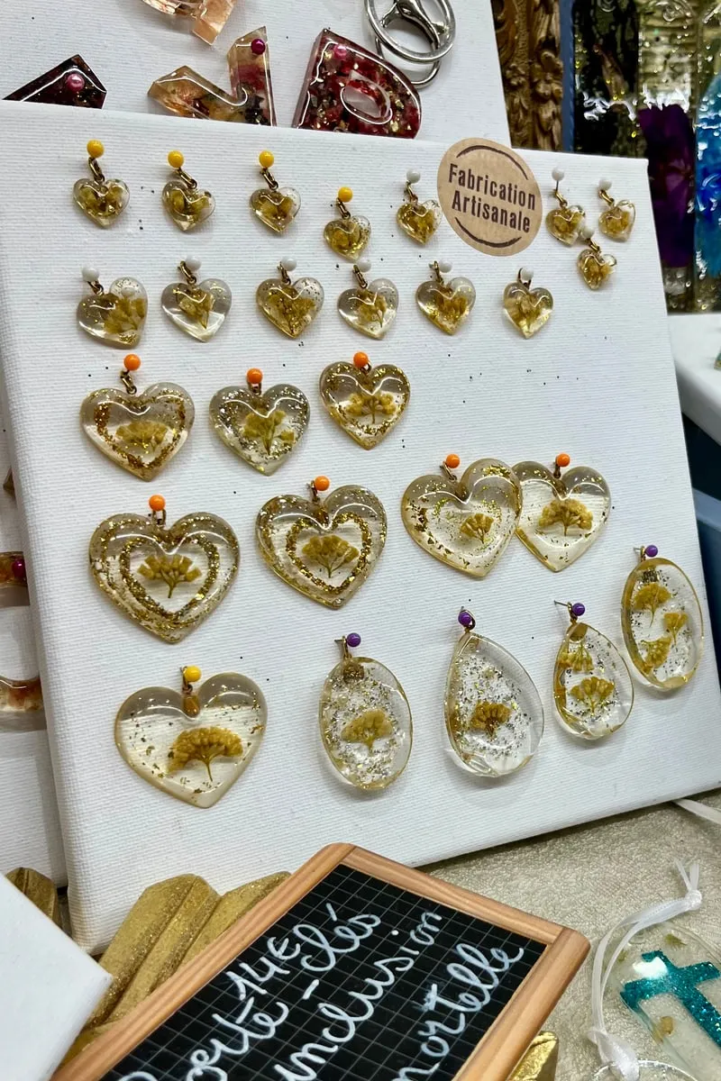 Boucles d’oreilles en résine transparente incrustées d’immortelle corse, présentées sur le stand Entre Ciel et Terre