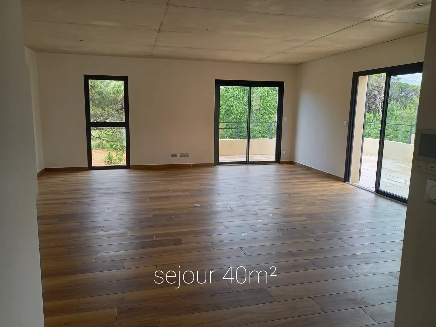 Le séjour de 40 m², parquet clair, trois baies vitrées dont deux donnant sur la terrasse