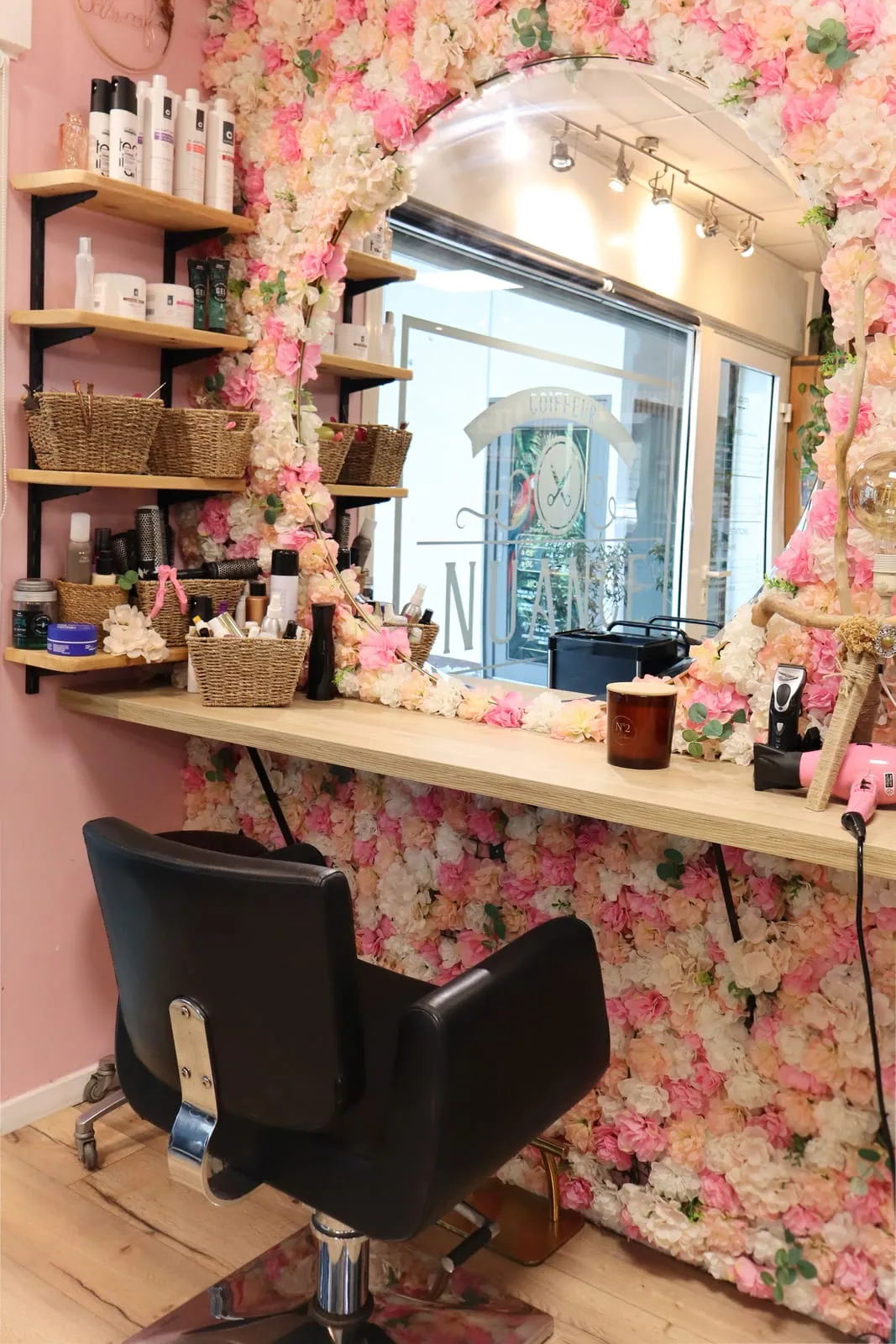 Le poste de coiffure du salon Nuance, devant son mur de fleurs roses et blanches
