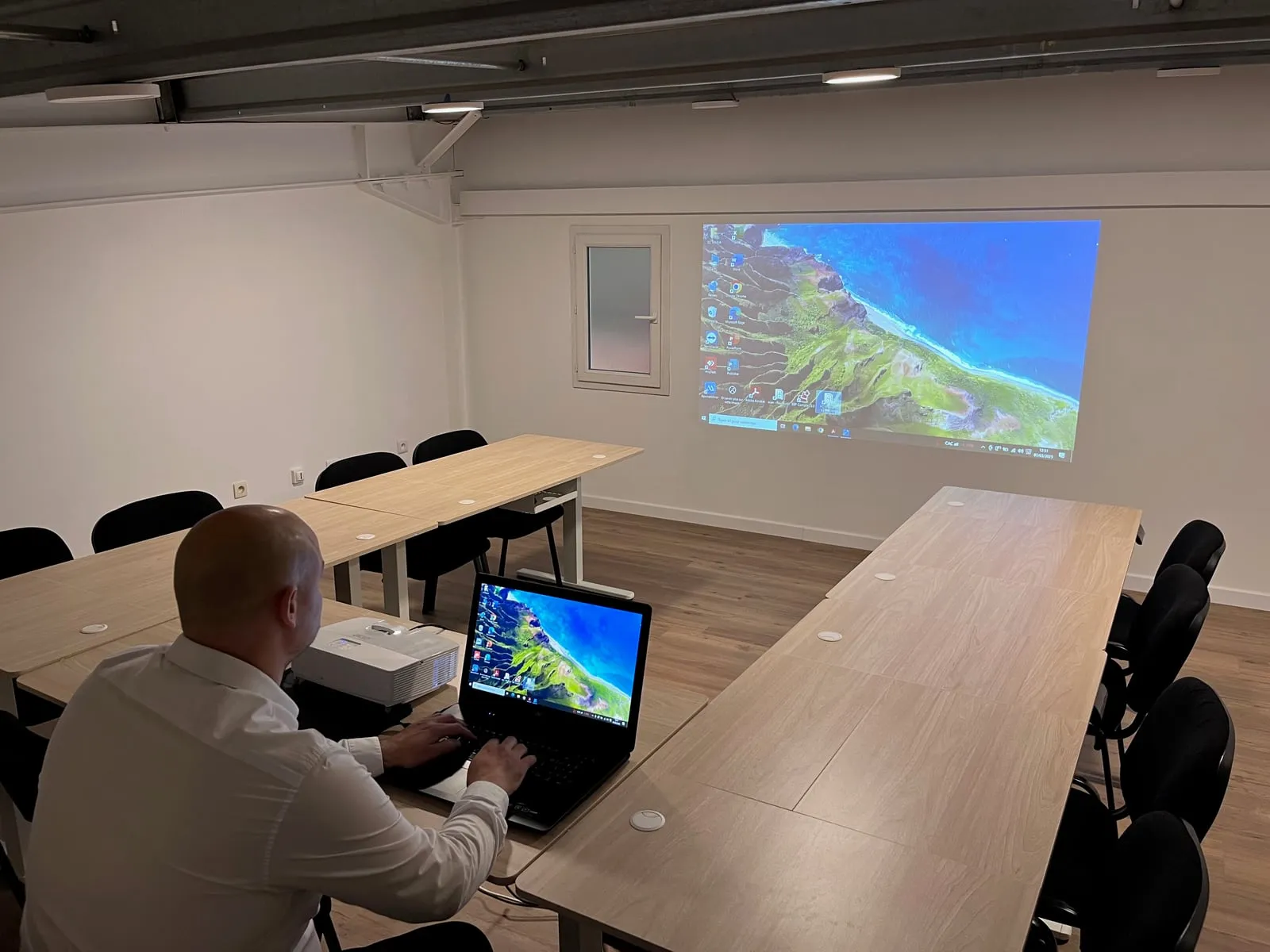 Une réunion en cours dans la salle, avec le vidéoprojecteur affichant un écran sur le mur