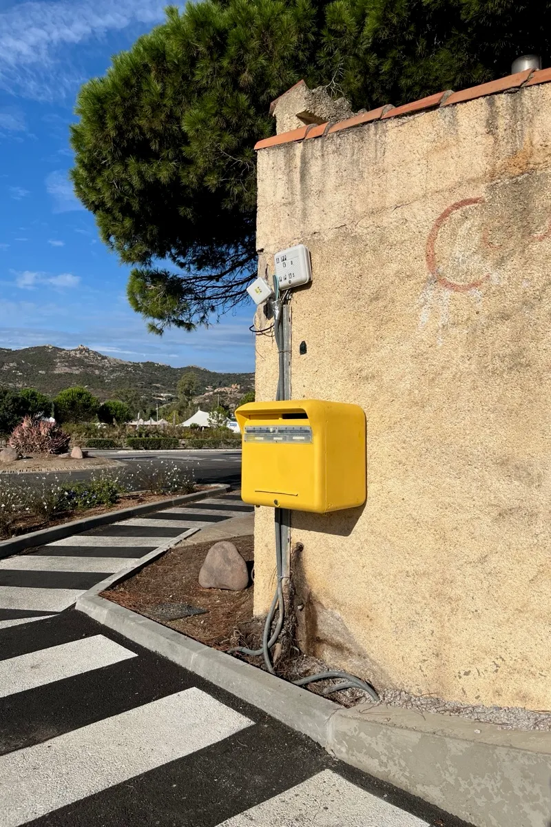 La boîte aux lettres jaune de La Poste, fixée au mur près du passage piéton