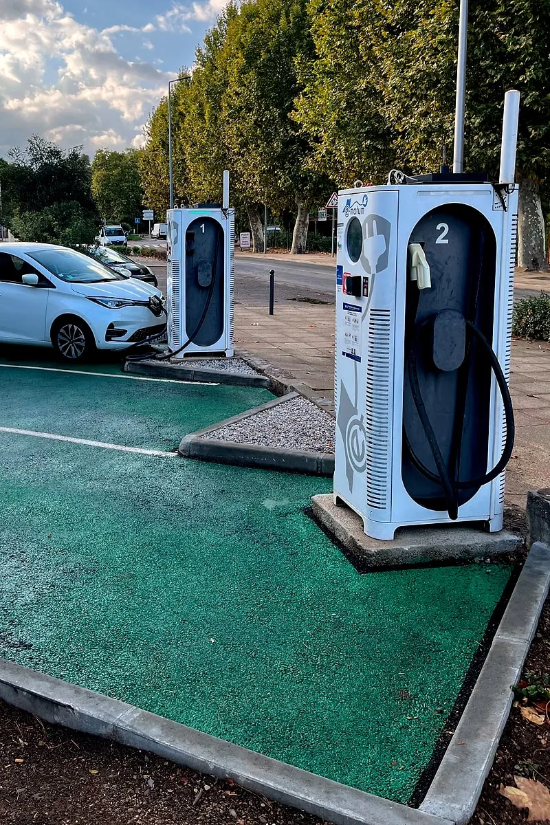 Les deux bornes de recharge E-motum du parking, avec une voiture électrique en charge sur son emplacement peint en vert
