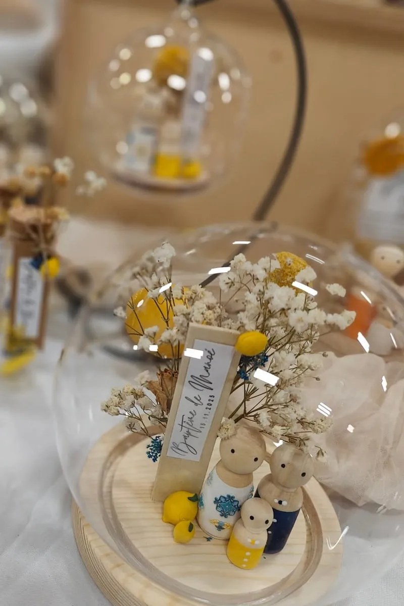 Globes en verre décorés de fleurs séchées et de petites figurines en bois, sur le stand So Elya