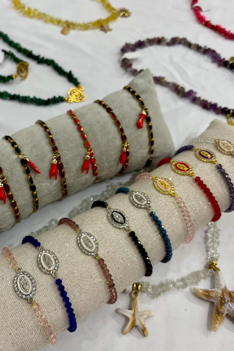 Bracelets et colliers Terra Corsa Bijoux présentés sur des coussins : mains de corail, médaillons et pierres colorées