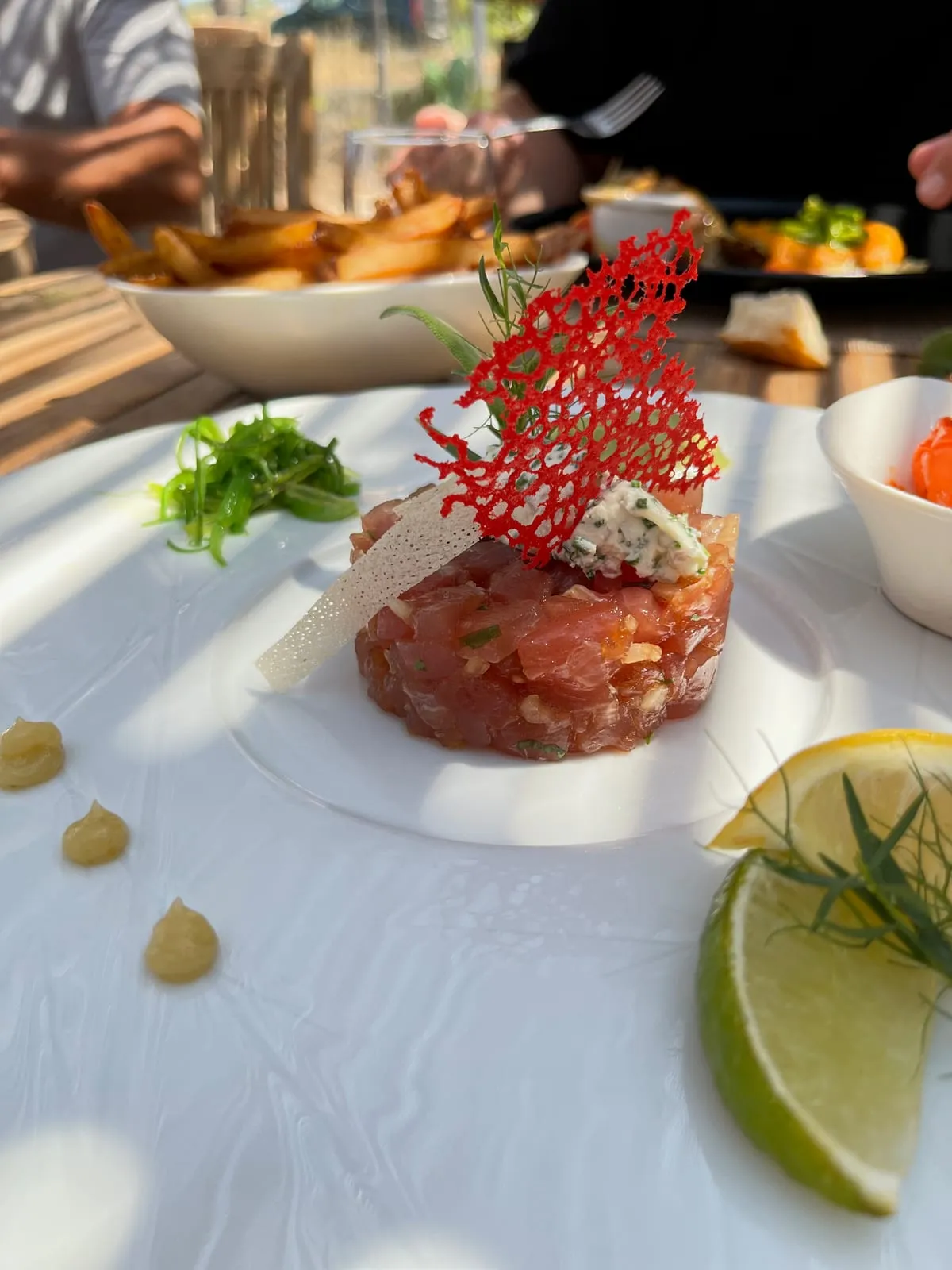 Un tartare de thon dressé à l'assiette, tuile croustillante, salade d'algues, citron et citron vert